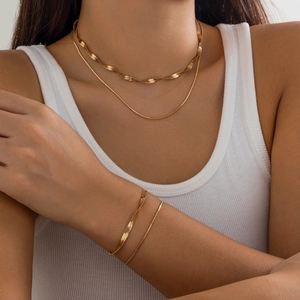 Double-layered golden snake chain necklace and bracelet jewelry set on female model