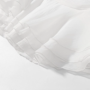 Close-up of white layered chiffon ruffles with fine rolled edges on a two-piece skirt set