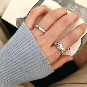 Detail shot of minimalist silver rings showing polished finish and twisted texture on fingers