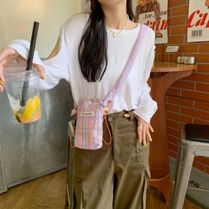 Mini checkered crossbody phone bag with purple strap shown in a casual cafe setting