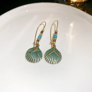 Detail of seashell and starfish dangle earrings with turquoise enamel on white ceramic tray