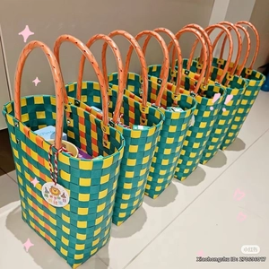 Detail of hand-woven checkerboard bucket bag with orange handles and cute gift tag