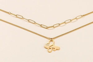 Detail of a gold-tone double-layered necklace featuring an abstract hollow butterfly pendant