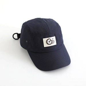 Detail of navy five-panel camping cap featuring white square patch and G letter embroidery