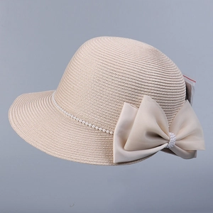 Détail d'un chapeau de paille beige avec nœud en satin élégant et bordure en perles blanches