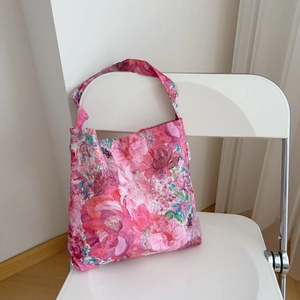 Floral cotton shoulder bag with pink and blue blossoms hanging on a white chair