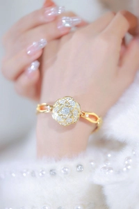 Macro detail of luxury gold flower bracelet watch with crystals and a soft pearly background