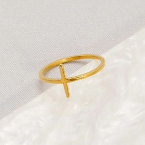 Minimalist gold stainless steel cross ring for women on a textured marble surface