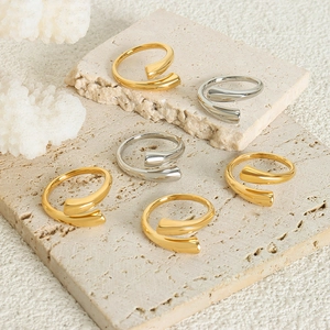 Minimalist polished gold and silver open rings set on natural stone display