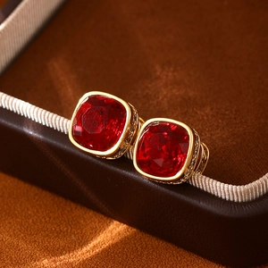 Vue macro de boucles d'oreilles dorées avec de grands cristaux rouges de coupe carrée