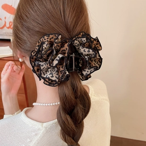 Rear view of a model wearing a leopard print fabric lace hair claw clip in a stylish bun