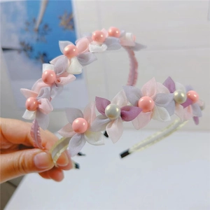 Close-up of pink and white chiffon flowers with pearl accents on a slim toothed headband