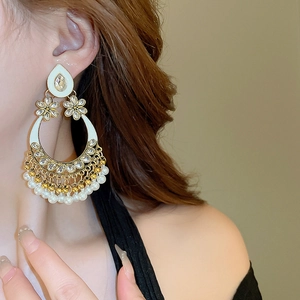 Detail of bohemian drop earrings with white enamel and pearl tassels worn on a model