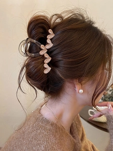 Detail of light brown heart claw clip with glitter finish and pearl earring accessory
