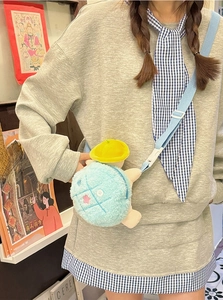 Detail of cute plush turtle crossbody bag with yellow hat and blue checkered zipper