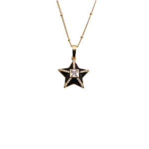 Close-up of a gold star pendant necklace with black zircon and central clear gemstone