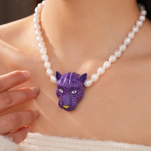 Vue détaillée d'un pendentif tête de panthère violette sur un collier de perles blanches