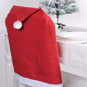 Detail of red Santa hat chair cover with white pompom on a wooden chair for Christmas
