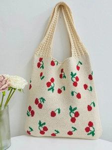 Close-up detail of knitted cherry pattern on a beige tote bag with a woven texture