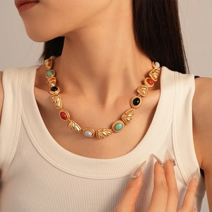 Close-up of vintage gold necklace with colorful triangular and oval gemstone inlays
