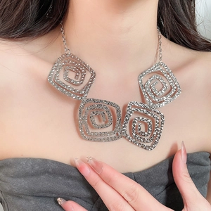 Macro shot of silver square spiral necklace showing textured geometric details on a model