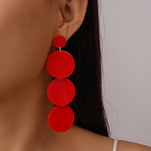 Detail of red tiered acrylic circular drop earrings shown on a model for scale