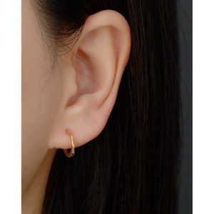 Close-up of minimalist gold knot hoop earrings worn on a model with natural lighting