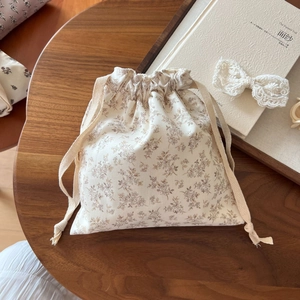 Detail of floral drawstring cotton pouch on a wooden table with vintage accessories