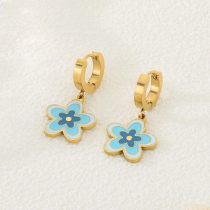 Details goldener Creolen mit blau-gelben Emaille-Blumenanhängern auf weißem Grund