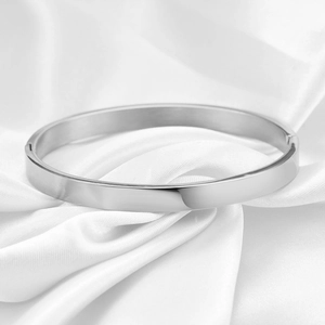 Close-up of polished 6mm silver stainless steel clasp bangle on elegant white silk fabric