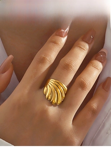 Gros plan d'une large bague en acier inoxydable doré avec texture coquille élégante