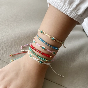 Set of 6 colorful Bohemian woven bead bracelets in beige, blue, and red on a wrist