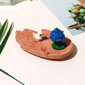 Detailed view of pink palm-shaped resin tray with mini duck and blue fruit tree decor