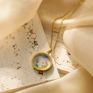 Gold plated evil eye pendant necklace with colorful crystals on a marble base