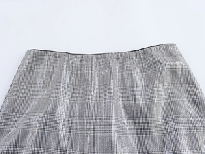 Gros plan de la taille d'une jupe grise à paillettes avec bordure noire et tweed