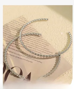 Macro shot of silver twisted cable texture on minimalist open bangle over a magazine