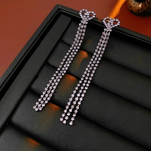 Détail de boucles d'oreilles pendantes argentées avec cœur et strass brillants