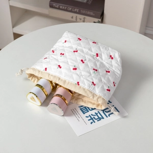 Detail view of cherry print quilted makeup bag showing drawstring and lipstick storage
