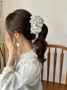 Close-up of a white polka dot chiffon scrunchie shown on a woman's hair in French style