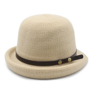 Detail of beige knitted bucket hat with vintage brown leather strap and gold rivets