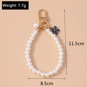 Detail of beaded pearl keychain with black flower charm and gold metal lobster clasp