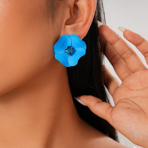 Close-up of blue floral stud earring with a square rhinestone on a model's ear