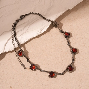 Close-up of gothic branch necklace with red gemstones on natural stone background