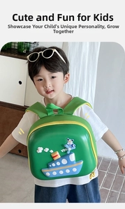 Detail of green hardshell toddler backpack featuring 3D cartoon ship and airplane patterns
