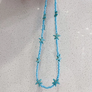 Detail of blue beaded necklace with starfish pendants and silver extension chain