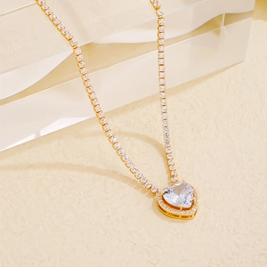 Close-up of golden tennis chain necklace featuring a brilliant heart-shaped crystal pendant