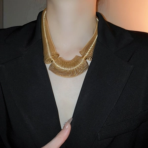 Detail of chunky gold spring coil necklace styled with a black blazer for a bold look