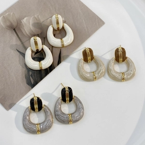 Vintage gold plated enamel earrings in white, beige and marble grey set on a white desk