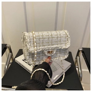 Detail view of white tweed crossbody bag with gold metal turn-lock and chain strap