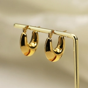 Detailed macro view of high-polish gold U-shaped hoop earrings on a metal display stand